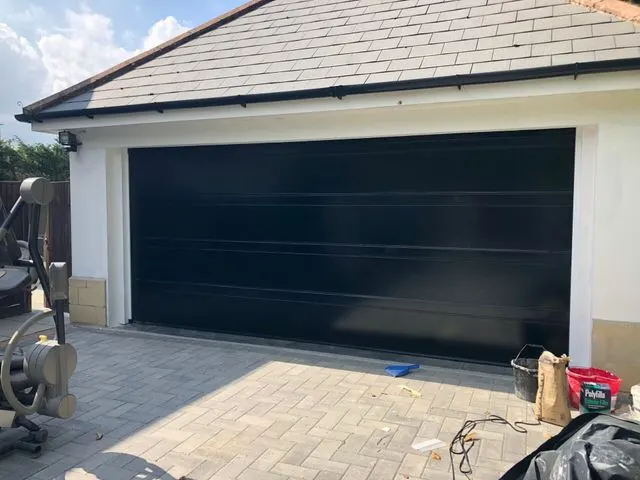 Black roller garage door fitted to a brick garage in Twickenham