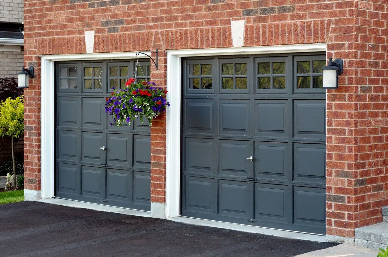 Two dark grey up and over garage doors on a brick house fitted by Doors 4 Garages Ltd